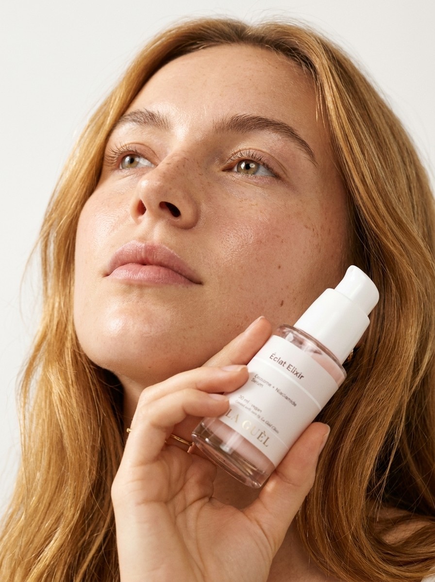 Kobieta trzymająca serum Éclat Elixir La Guèl blisko policzka, naturalna skóra